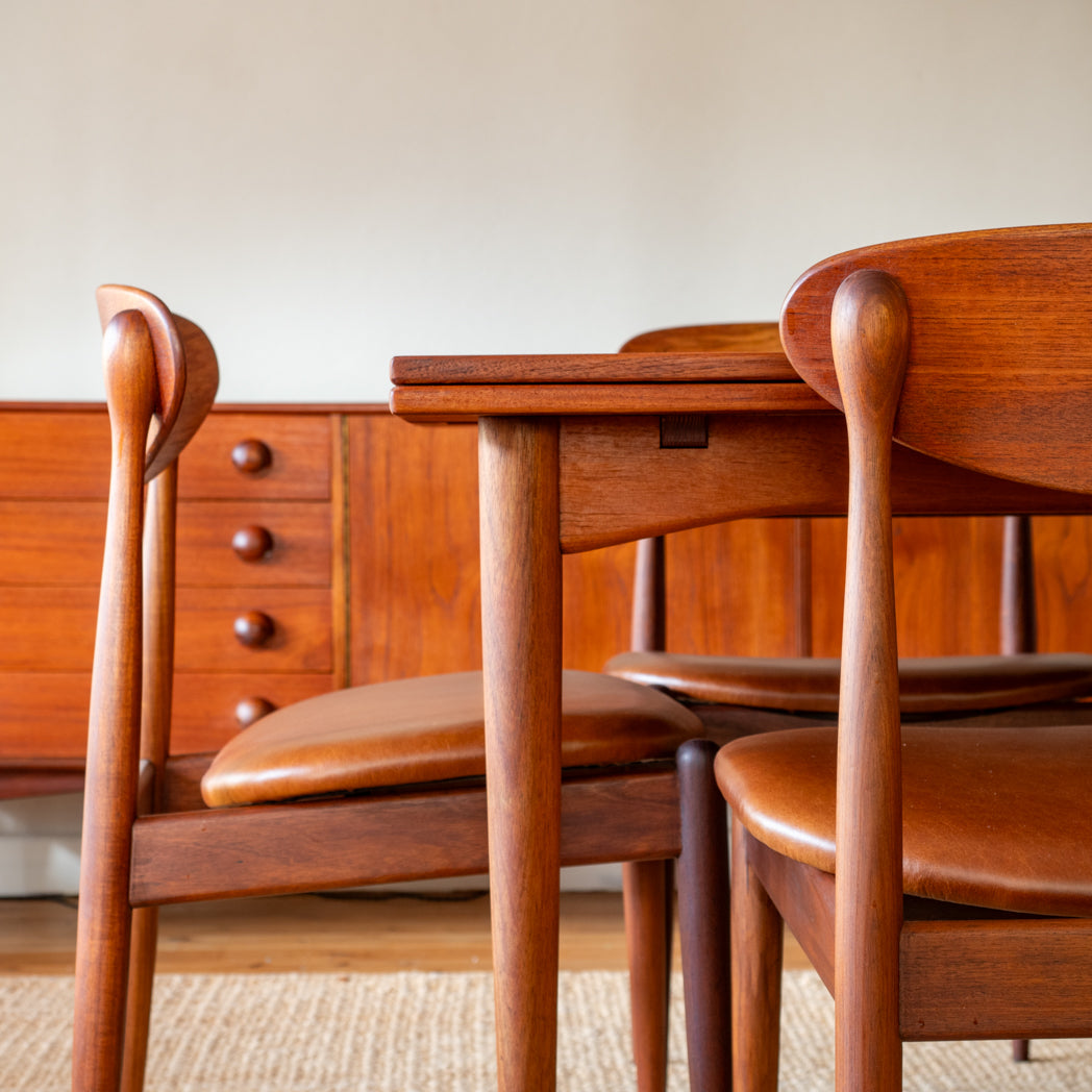 Wooden dining table with chairs in a room with wooden cabinets.